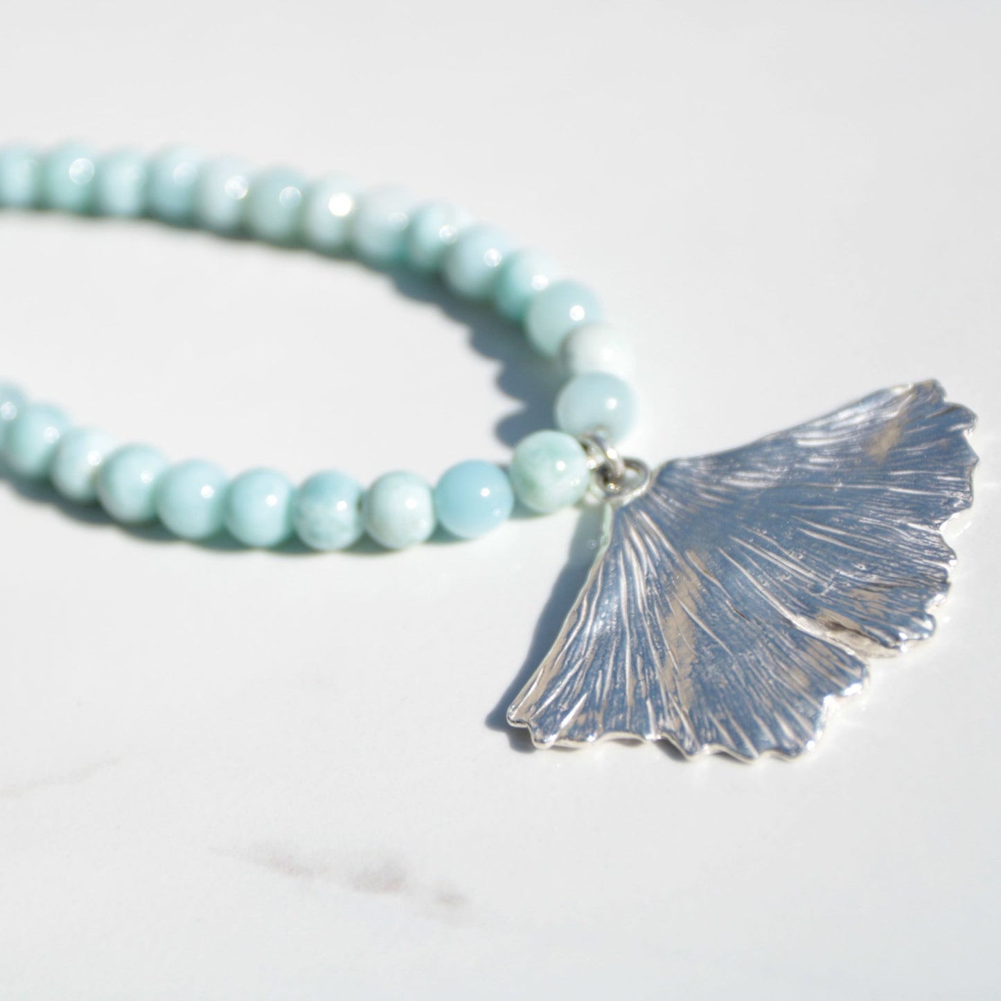 handmade fine silver ginkgo leaf pendant on a strand of aquamarine 8mm beads fasted with a sterling silver toggle clasp carrie foscato design made in USA